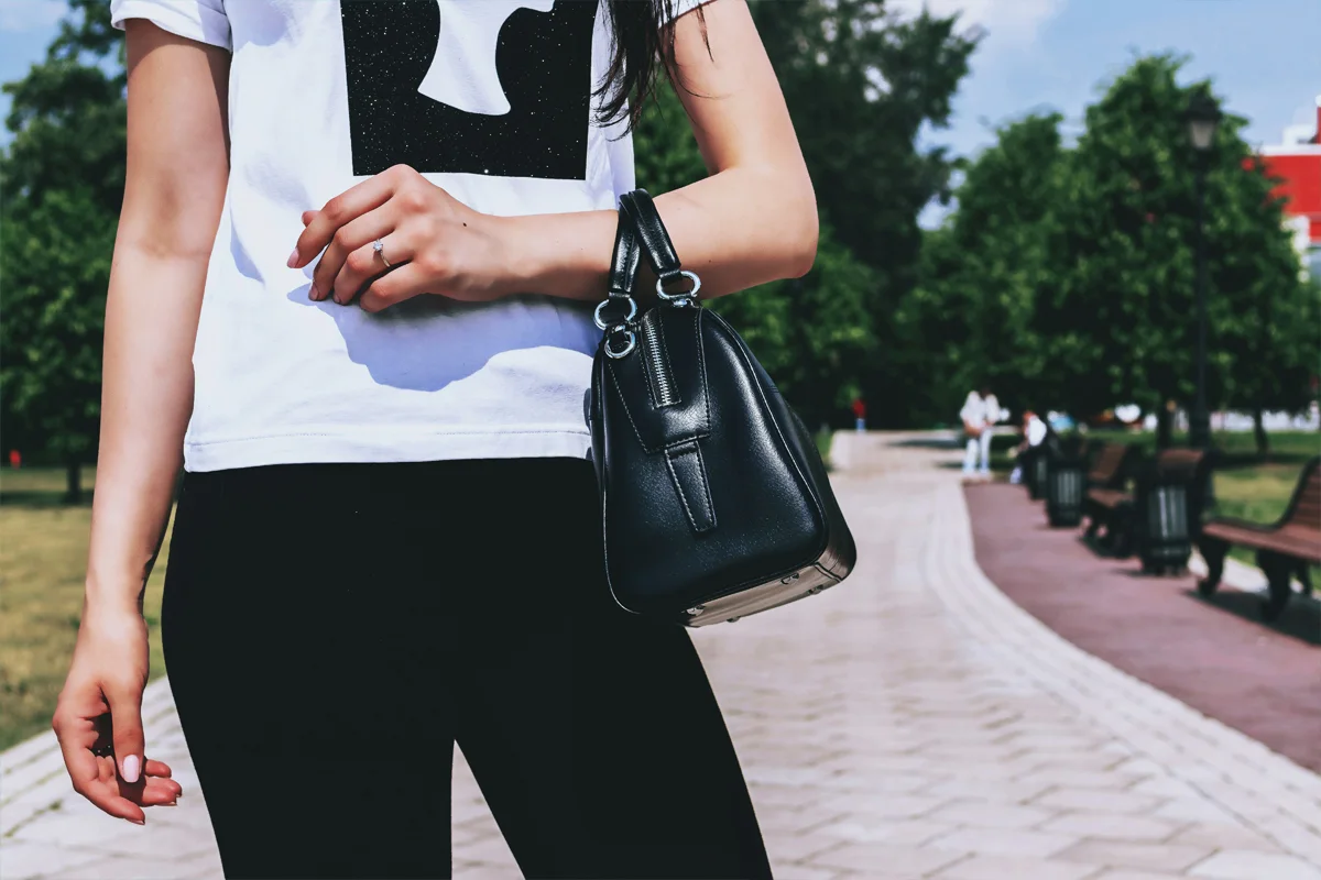 Petit sac à main noir en cuir porté au bras avec une tenue décontractée en ville