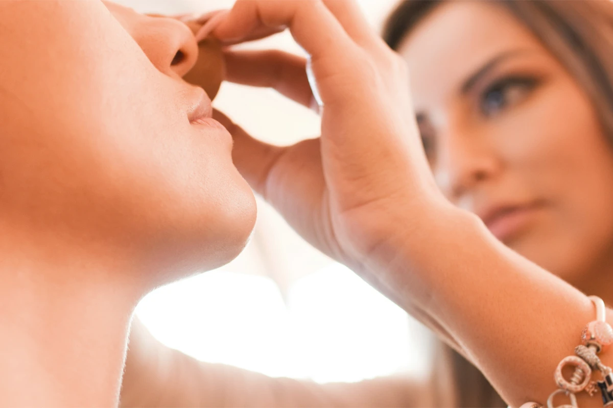 Deux femmes lors d’un soin du visage, l’une appliquant délicatement un produit cosmétique sur le visage de l’autre