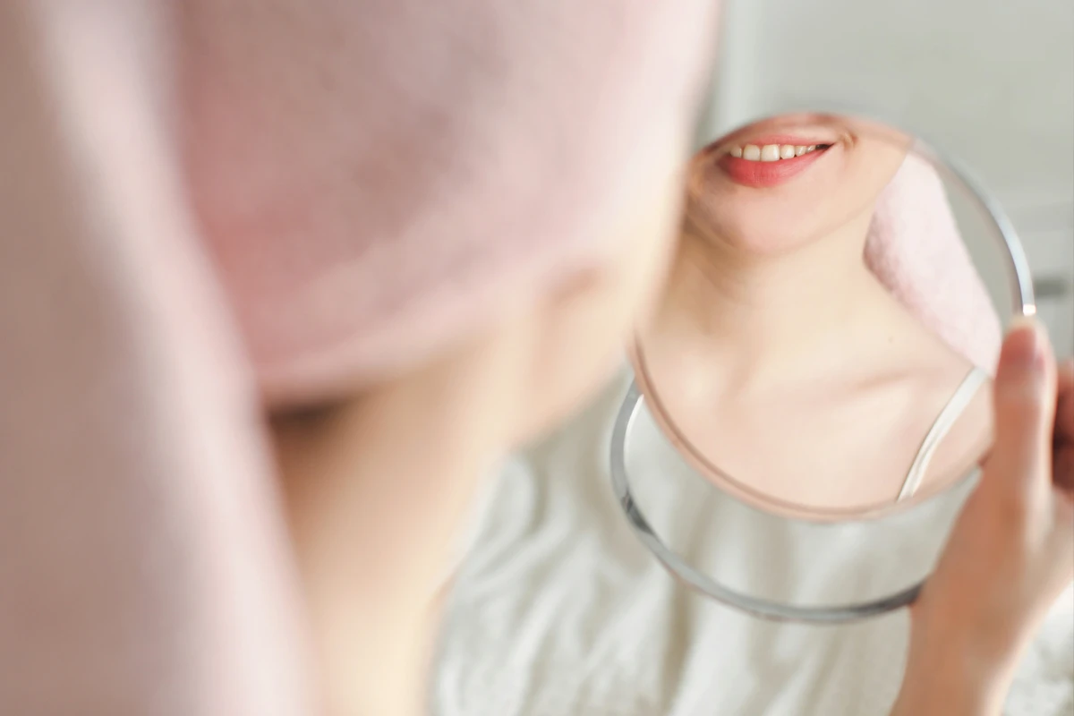 Femme observant sa peau dans un miroir lors de sa routine beauté